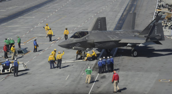 Largement couvé par les personnels du pont d'envol, ce F-35C a les ailes en partie repliées.