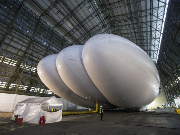 CARRINGTON, ENGLAND - FEBRUARY 28:  Mike Durham, the Technical Director at Hybrid Air Vehicles, admires the helium-filled 'Airlander' aircraft in a giant airship shed on February 28, 2014 in Cardington, England. The Airlander, which was originally developed for the US military before the project was cancelled due to budget cuts, is the world's longest aircraft at 92 meters. Although slow moving compared to conventional aircraft, the Airlander is able to carry large payloads over long distances very efficiently. Hybrid Air Vehicles' project to develop the technology further is being funded by a Government grant as well as private finance from individuals including Bruce Dickinson, the lead singer of the band Iron Maiden.  (Photo by Oli Scarff/Getty Images)