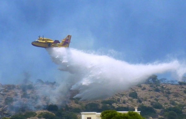 Bombardier CL-415 grec larguant sa charge d'eau sur une cible péri-urbaine.