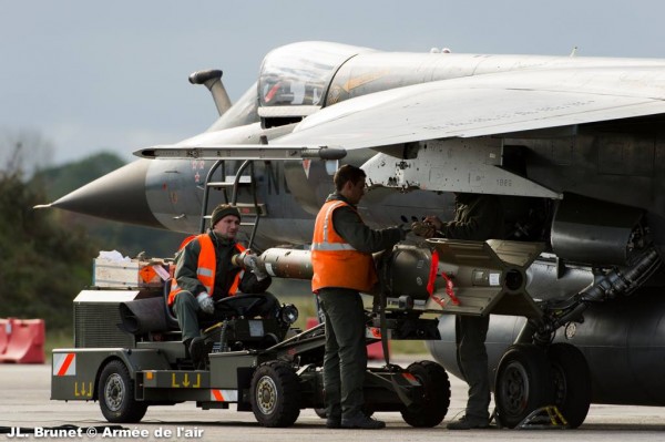 Deux armuriers gréent un Mirage F1-CR au moyen d'une arme à guidage laser GBU-16 d'origine américaine.